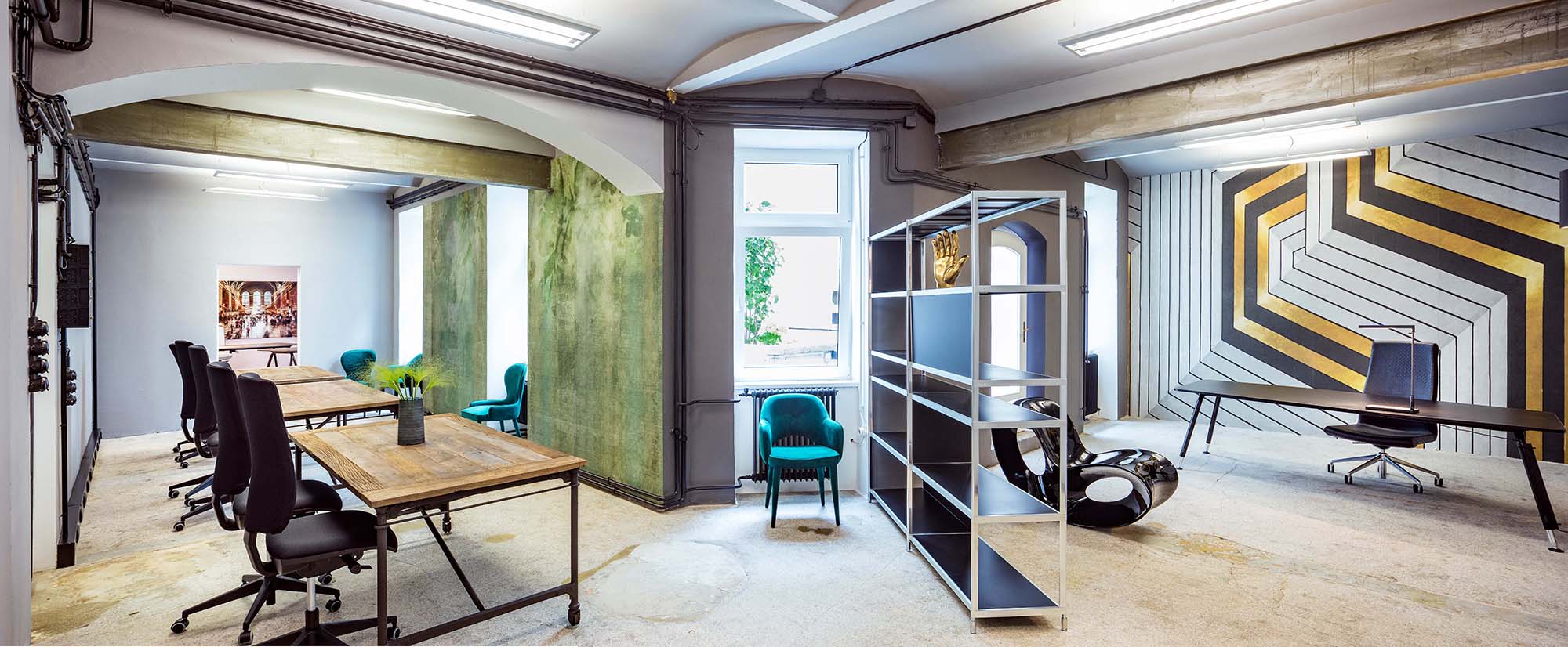 Tapeten, Farben und außergewöhnliche Möbel, wie der schwarze Hochglanzsessel Void von Magis, machen aus dieser Souterrain-Fläche ein junges, urbanes Office.