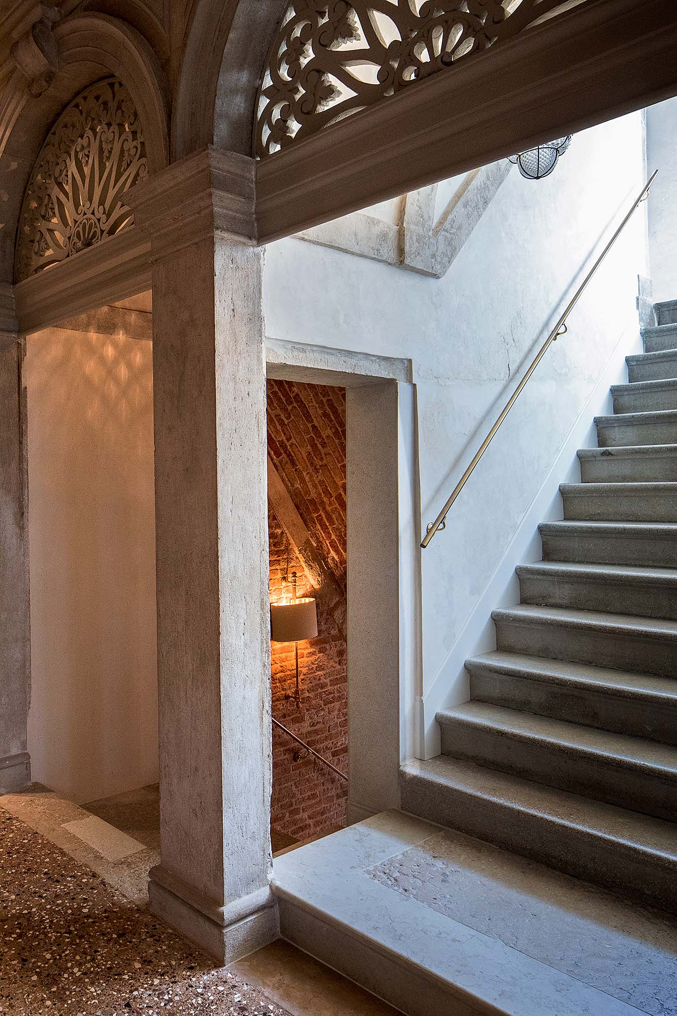 Restaurierter, Treppenaufgang, mit roter Ziegelwand und warmer Beleuchtung, mit aufwendig restaurierten Rundbogendurchgängen