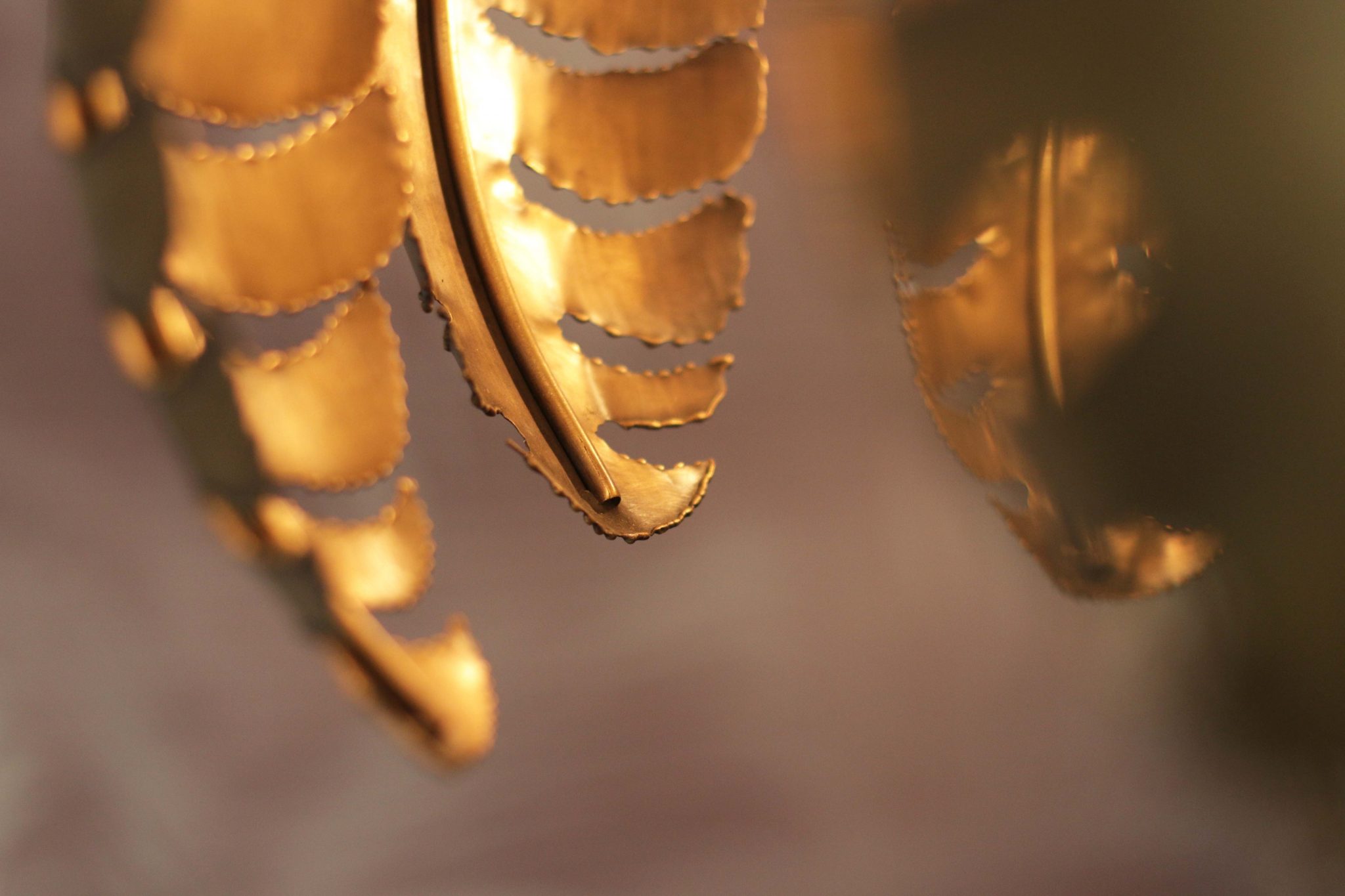 Nahaufnahme von goldenen, das Licht reflektierenden Palmenblättern aus Metall.