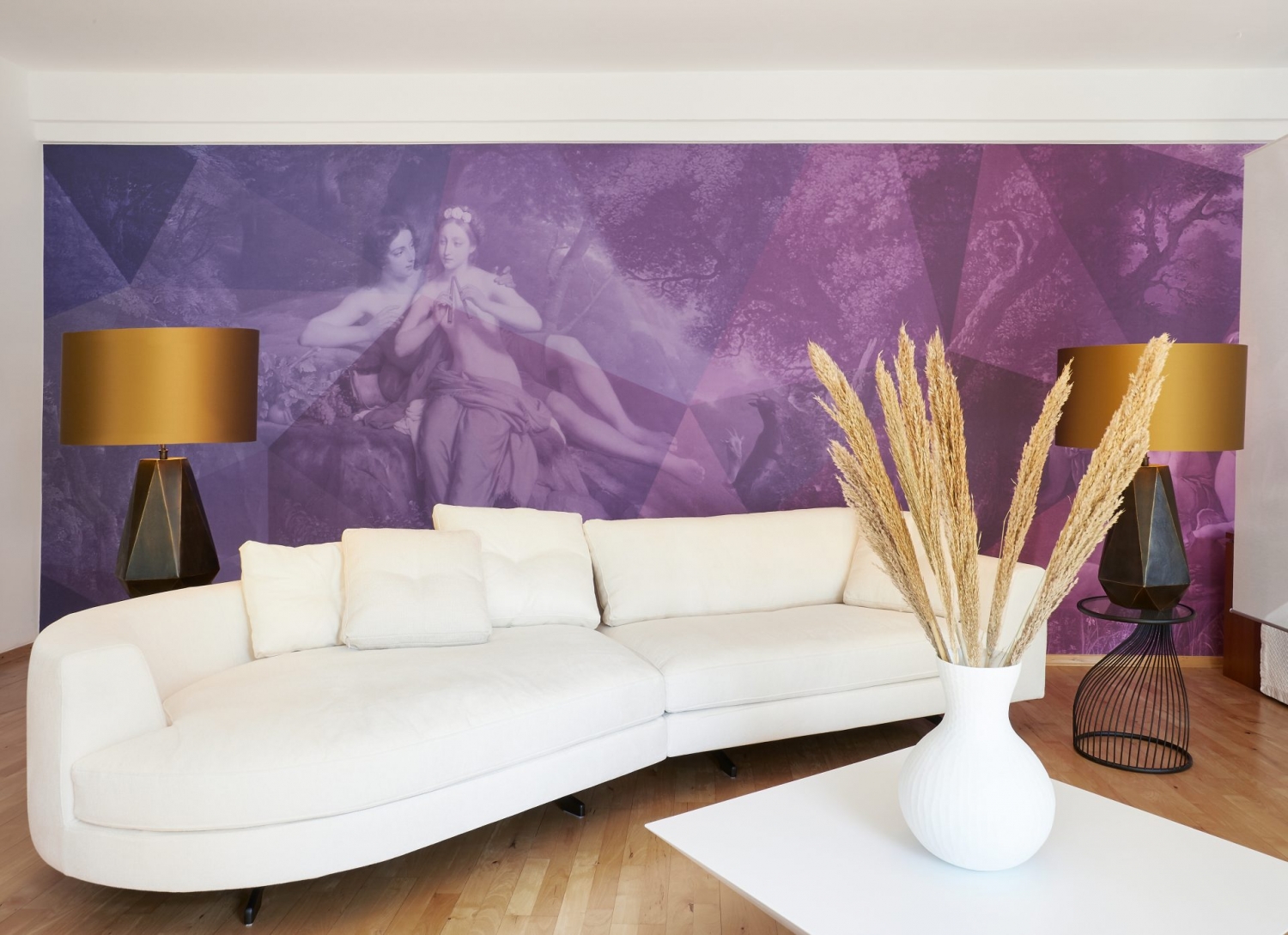Wohnzimmer mit langem, geschwungenem, weißem Sofa von Valentini, Tischlampen mit schwarzem Fuß und goldenem Schirm, violetter Tapete mit Landschaftsmotiv und zwei Frauen
