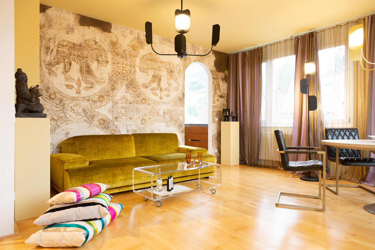 Wohnzimmer mit Interior Design in Gelb- und Ockertönen, Tapete mit Großkatzenmotiv, Asiatische Dekorationselemente und ausgefallenen Deckenlampen.